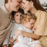 A loving family of four shares a tender moment in a cozy indoor setting, embracing and smiling.